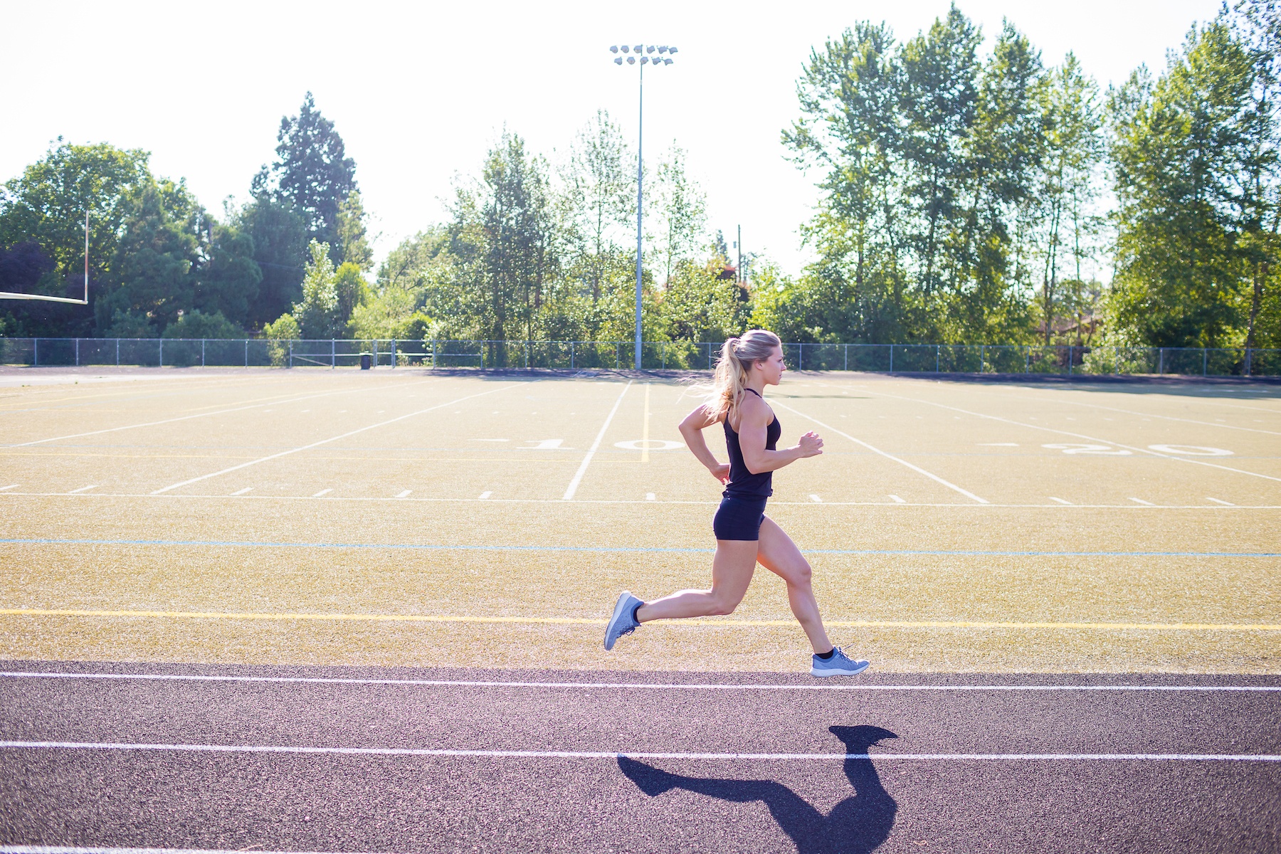 Female runner performs short sprints while working out on an outdoor track in the summer.