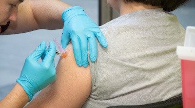 A person receiving an injection in their arm.