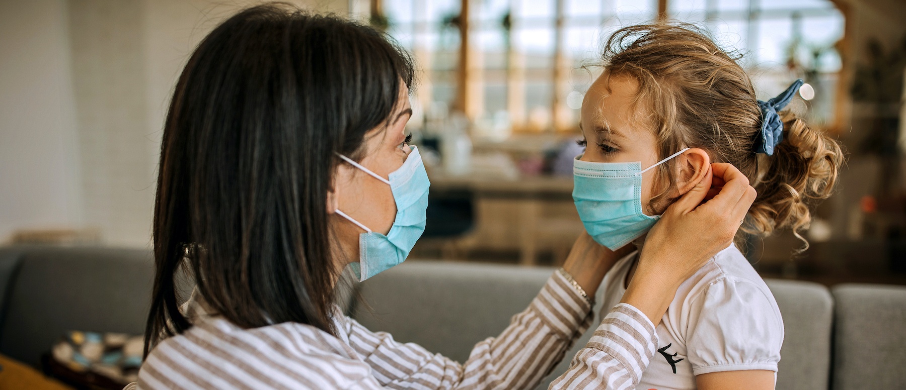Mother putting protective mask on her daughter's face