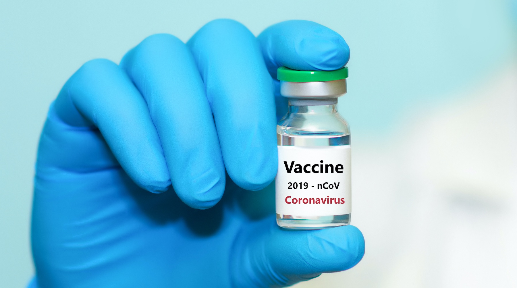 A gloved hand holds a SARS-CoV-2 vaccine vial