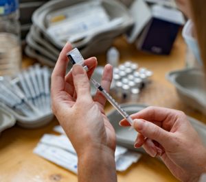 Hands drawing a dose of vaccine into a syringe