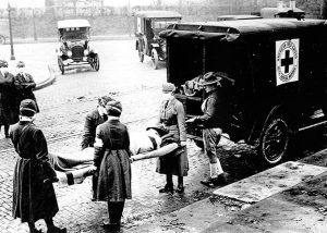 American Red Cross nurses load a patient onto an ambulance during the 1918 influenza pandemic. 