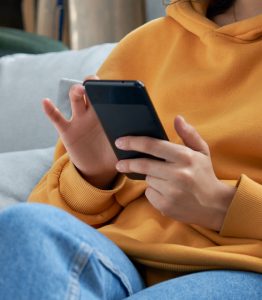 Happy teen girl checking social media holding smartphone at home.