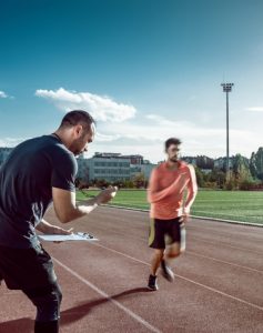 Track and field runner with coach timing his lap